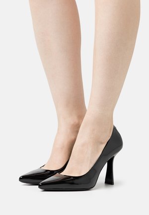 Černé lakované lodičky na vysokém podpatku s špičatou špičkou, elegantním designem a tenkým jehlovým podpatkem. Hladká textura s lesklým povrchem.