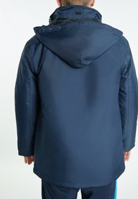 Tamsiai mėlyna nepralaidi vandeniui striukė su kapišonu, turinti lygią tekstūrą ir tiesų kirpimą. Apima minimalų aparatūrą ir švarų dizainą.