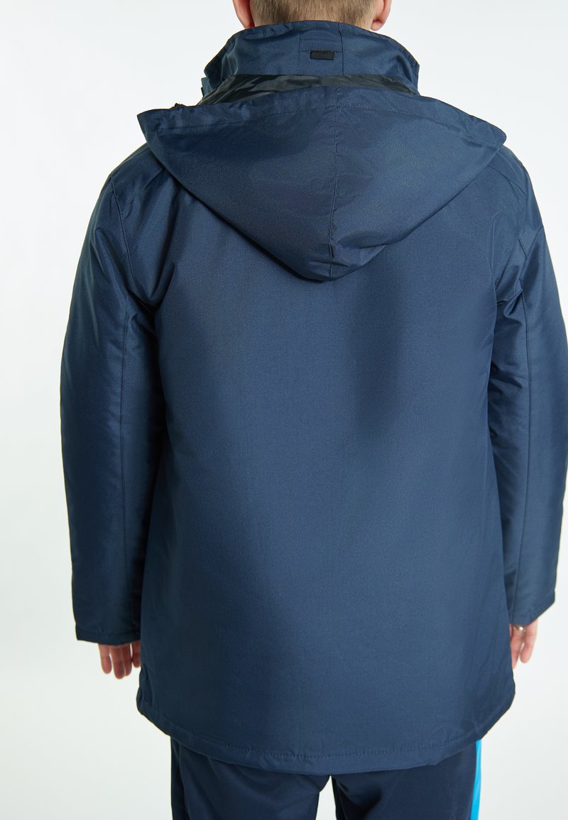 Tamsiai mėlyna nepralaidi vandeniui striukė su kapišonu, turinti lygią tekstūrą ir tiesų kirpimą. Apima minimalų aparatūrą ir švarų dizainą.