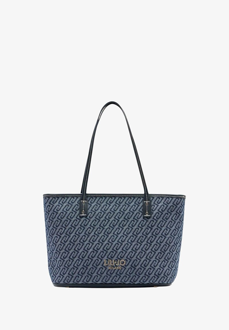 Tygkasse i marinblått tyg med mönstrad design. Svarta läderhandtag och detaljer, med en gyllene logotyp på framsidan.