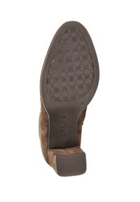 Semelle en cuir suédé marron avec un grip en caoutchouc à motif, talon bas, et marquage "unisa" dans la zone de la voûte.