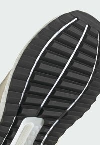 Sole tenisky s černou gumovou spodní částí, obsahující hluboké drážky, bílou akcentní linku a texturovaný povrch pro lepší přilnavost.