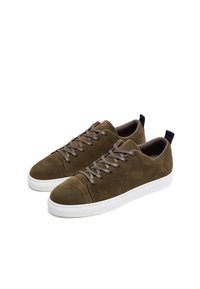 Zapatillas de ante marrón con puntera redonda, cordones grises, suela de goma blanca y pequeño tab negro en el talón. Diseño sencillo con mínima marca.
