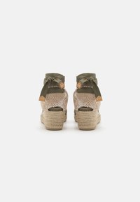 Espadrille wedge sandalen met een geweven beige stoffen bovenkant en olijfgroene striklinten. Beschikt over een jute-wikkel hak en een open achterkant ontwerp.