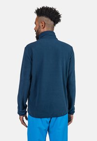 Pullover in pile blu navy con colletto alto e maniche lunghe; texture morbida, orlo arrotondato e vestibilità rilassata.