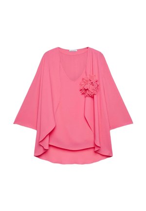 Różowa damska bluzka z luźnymi rękawami i ozdobnym materiałowym kwiatem na piersi, prezentowana na białym tle.