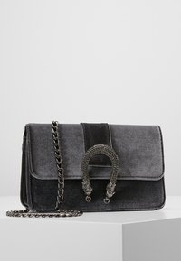 Borsa in velluto grigio con tracolla a catena, dotata di una maniglia intrecciata e di una patta pieghevole. Design minimalista con texture e lucentezza sottili.