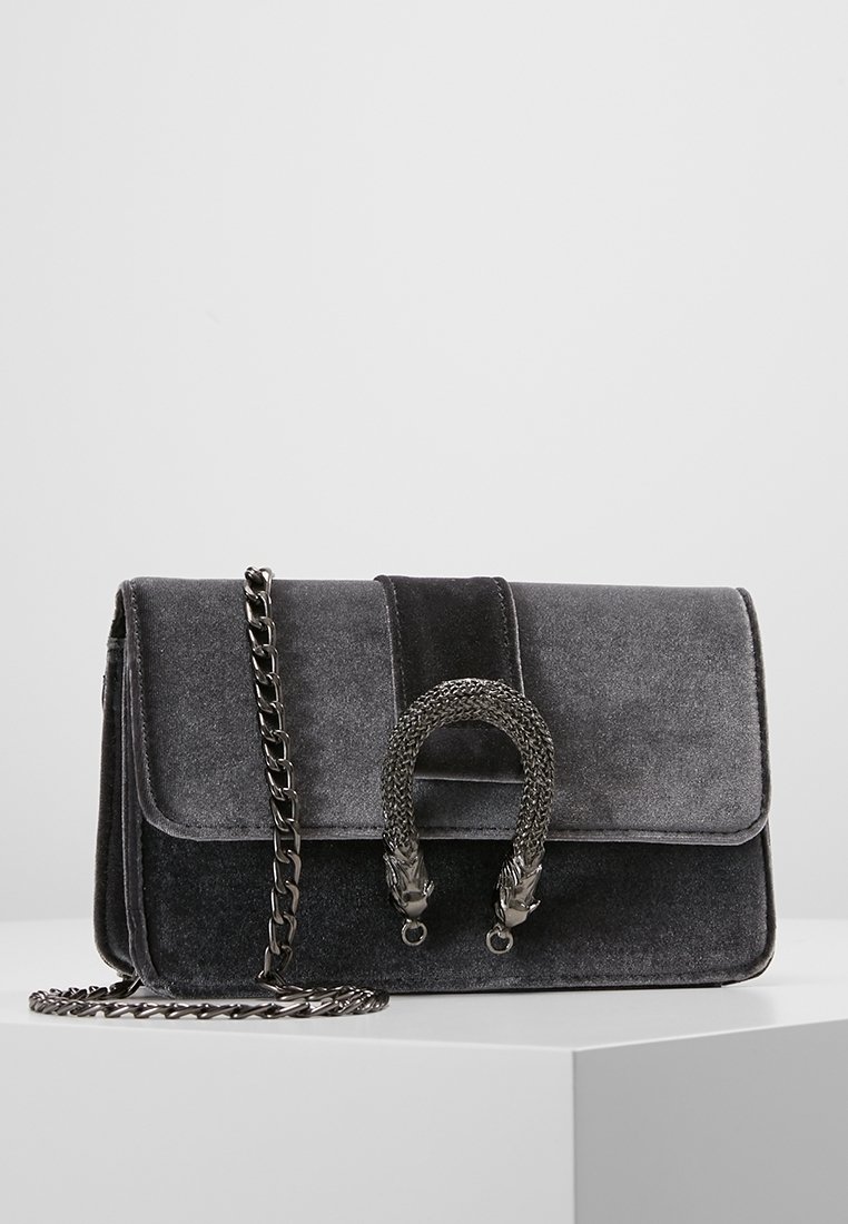 Borsa in velluto grigio con tracolla a catena, dotata di una maniglia intrecciata e di una patta pieghevole. Design minimalista con texture e lucentezza sottili.