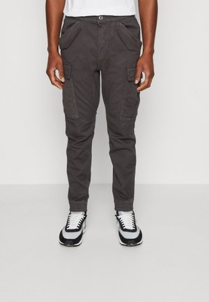 Szare spodnie cargo w fasonie slim fit z bocznymi kieszeniami, szlufkami na pasek i zwężanymi nogawkami, w połączeniu z czarno-białymi sneakersami.