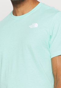 Světle tyrkysové tričko s krátkým rukávem z měkké bavlny, na hrudi s malým bílým logem "The North Face".