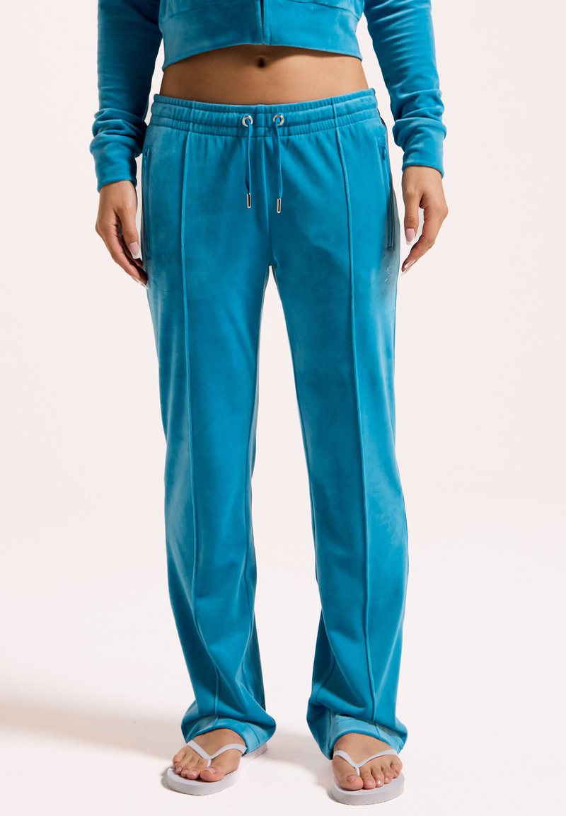 Türkise Velours-Sweatpants mit elastischem Bund, seitlichen Taschen und vertikalen Nähten für zusätzliche Textur. Ausgestellte Beinform.