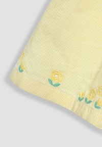 Gestreifter gelber Stoff mit gestickten Blumen. Merkmale sind eine glatte Textur und florale Akzente in Gelb und Grün am Saum.