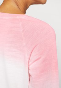 Persona che indossa una camicia di tessuto con sfumature di rosa e bianco, mostrata da dietro, con un'attenzione particolare ai dettagli delle spalle e del colletto.