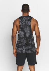 Czarny top na ramiączkach z dużym otwartym plecami i subtelnym wzorem palmowym. Połączony z ciemnymi szortami, prezentującymi wygodny sportowy design.