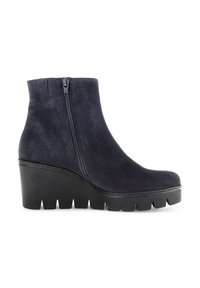 Bottes de cheville en suède bleu marine avec une fermeture éclair sur le côté, un talon en wedge et une épaisse semelle en caoutchouc noire dotée d'un bord cranté pour l'adhérence.