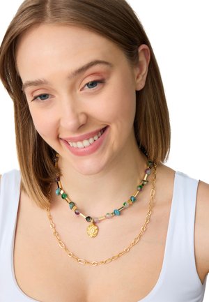 Collana multilivello con perline colorate e accessori in oro, con una catena decorata da un pendente.