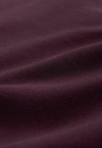 Țesătură bordo închis cu suprafață texturată, prezentând un model țesut. Drapaj neted și strălucire subtilă care îi îmbunătățesc aspectul.