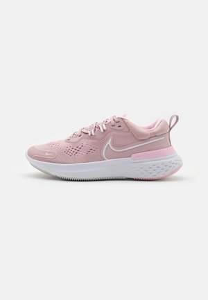 Baskets de sport roses avec une tige en mesh, semelle rembourrée et accents blancs. Présente des motifs texturés et un petit tabouret au talon pour un enfilage facile.