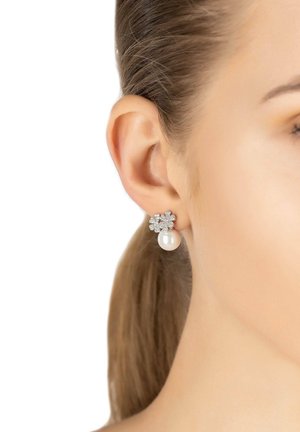 Boucles d'oreilles en métal argenté présentant un design de fleur avec des cristaux transparents et une goutte de perle blanche. Accents texturés avec une finition polie.