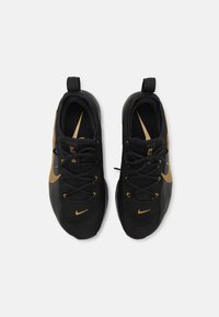 Black athletic shoes with gold accents, textured upper, laces, and looped pull tabs. Features a Nike swoosh on each side.