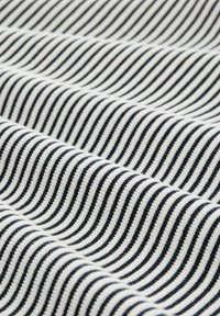Tissu rayé avec un motif ondulé, présentant des lignes noires et blanches alternées. La texture est uniforme et tissée, affichant un léger éclat.