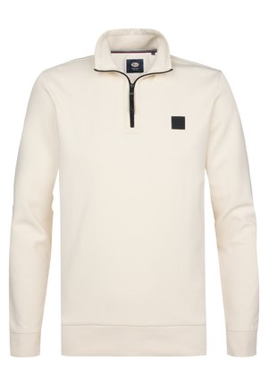 Jersey de manga larga color crema con cremallera negra en el cuarto superior y pequeño logo cuadrado negro en el pecho izquierdo.