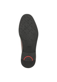 Sole di scarpa in gomma nera con motivo di grip testurizzato, accento rosso circolare e logo del marchio. Margine superiore in pelle liscia visibile.