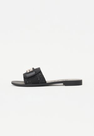 Sort slip-on sandal med tekstureret stofrem, der har en dekorativ spænde. Flad sål med minimal mønster og åben tå-design.