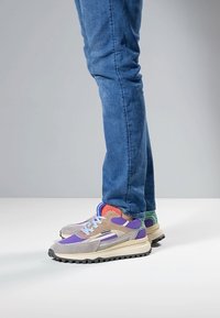 Moniväriset lenkkarit, joissa on yhdistelmä mokka- ja verkkopintoja, sävyinä violetti, harmaa ja sininen. Kuvioitu pohja parempaan pitoon.