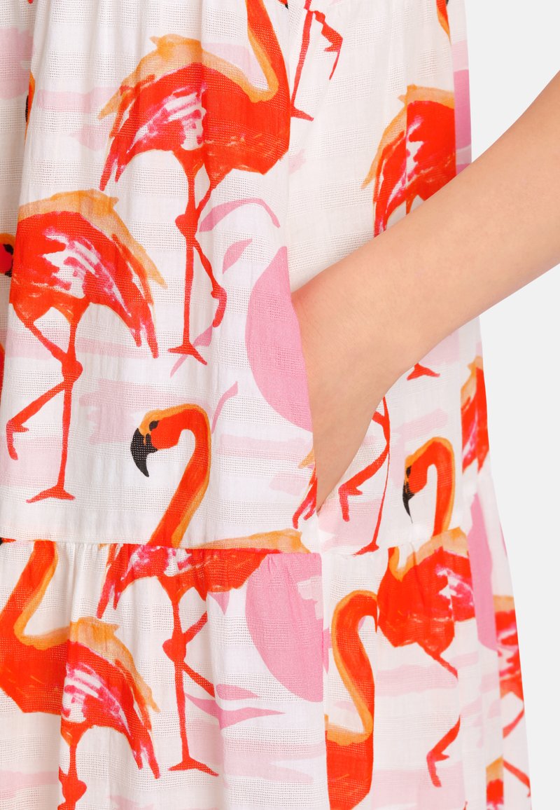 Flamingo-Print Kleid mit leuchtend roten und rosafarbenen Farbtönen auf einem hellen Stoff. Auffällige Elemente sind eine Tasche und ein gestuftes Design.