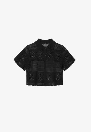 Czarna, krótka, szydełkowana koszula z kołnierzykiem, zapinana na guziki z przodu, ozdobiona kwadratowymi wzorami z wyciętymi literami na przodzie i rękawach.