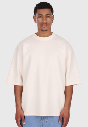 T-shirt oversize rosa chiaro realizzato in tessuto morbido, con maniche corte e larghe e scollo rotondo. Logo discreto sulla manica.