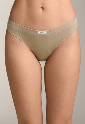 Beige ribbed bikini-style underwear with a small white "OYSHO" label centered on the waistband worn by a person with bare midriff and thighs.