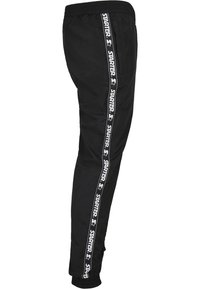 Schwarze Sporthose mit schmalem Schnitt, elastischem Bund und elastischen Bündchen. Mit weißen "STARTER"-Logobändern an den Seiten.