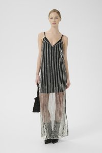 Rochie maxi neagră cu un overlay transparent, prezentând accente verticale asemănătoare cu perle albe. Include un decolteu în V și bretele subțiri, asortată cu o geantă mică neagră.
