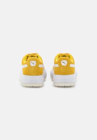 Gula mockaskor med vita accenter, med en vadderad krage och tunga, perforerad detaljer och en gummisula.