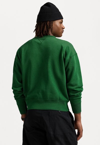 Green sweatshirt with ribbed cuffs and hem, featuring a rounded neckline and textured fabric, worn with black cargo pants.