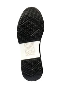 Semelle de chaussure en caoutchouc noir avec une surface texturée présentant des motifs ondulés et des formes hexagonales. Comprend des marquages d'instructions en blanc.