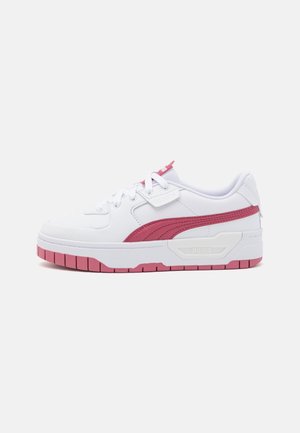 Baskets basses blanches et roses avec laçage à l'avant, bande logo Puma rose et semelle en caoutchouc rose, vues de côté sur fond blanc.