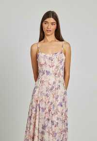 Florale maxi-jurk met dunne bandjes. Crème basis met paarse, roze en groene bloemenprint. Lichtgewicht stof, vloeiende silhouet en afgeronde halslijn.