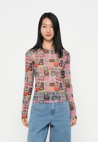 Langermet mesh topp med fargerike, grafiske trykk i ulike former mot en rosa bakgrunn. Designet for en tettsittende silhuett.