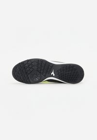 Suela de zapato atlético negra con una superficie de goma texturizada, que presenta patrones triangulares y un diseño de acento blanco.