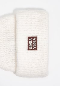 Diadema de invierno de punto suave blanca con un borde doblado y una etiqueta rectangular marrón que dice "BIMBA Y LOLA" en texto blanco.