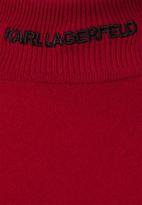 Maglione rosso lavorato a maglia con colletto a coste. Logo "KARL LAGERFELD" ricamato in nero vicino al collo. Texture liscia e forma aderente.