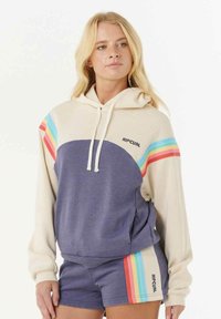 Hoodie met crème- en marineblauwe secties, met regenboogstrepen op de mouwen en het "RIPCURL"-logo op de borst. Zachte stof, ontspannen pasvorm.