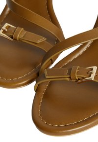 Sandalias de cuero marrón con correas delgadas y detalle de hebilla en tono dorado. Textura suave y costuras visibles en la suela. Diseño minimalista.