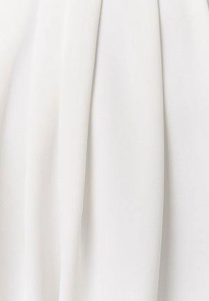 Balts audums ar mīkstām, plūstošām krokām un smalku teksturētu rakstu, kas rada maigas vertikālas ēnas un gaismas atspīdumus.