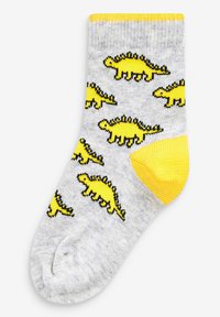 Graue Knöchelsocken mit gelben Dinosauriermustern und schwarzen Umrissen. Gelbe Akzente an der Borte und den Zehen mit geripptem Muster.