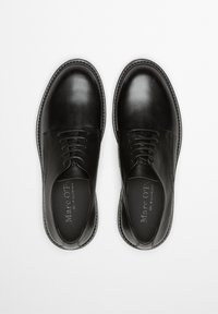 Czarne skórzane buty o gładkiej fakturze, zaokrąglonym nosku i pięciu dziurkach na sznurowadła. Charakteryzują się delikatnym przeszyciem i płaską podeszwą.