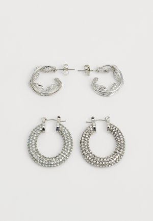 Two pairs of silver earrings: one pair with textured leaf design, the other with a circular shape adorned with sparkling rhinestones.